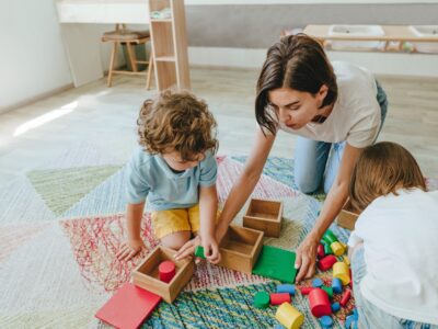 Young,Woman,Teacher,Playing,In,A,Kindergarten,With,Children,On